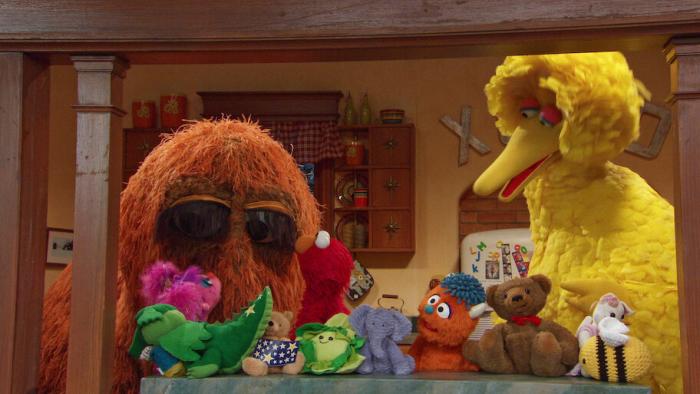 Storm On Sesame Street TV: Abby and Elmo listen to their friends in a kitchen with colorful stuffed toys on a table.