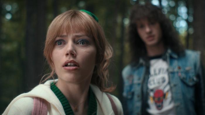 Stranger Things Season 4 screenshot 2: Crissy stares at something off-camera in wide-eyed horror, while Eddie is out of focus behind her