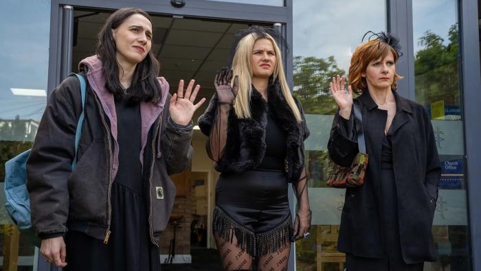 Such Brave Girls TV show screenshot 2: Kat Sadler, Lizzie Davidson, and Louise Brealey are dressed in all black as they wave.