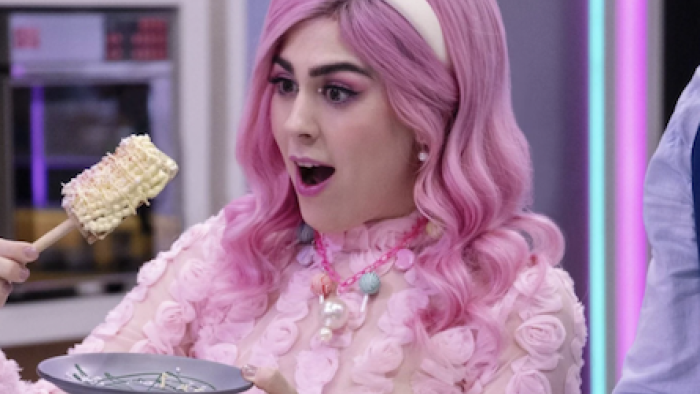 Sugar Rush: The Baking Point TV show  screenshot 2:  A pink haired Gris Verduzgo tries a corn on a stick shaped dessert. 