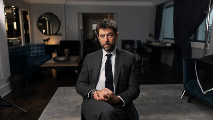 Andre Agnelli sitting in a chair wearing a dark suit in Super League: The War for Football. 