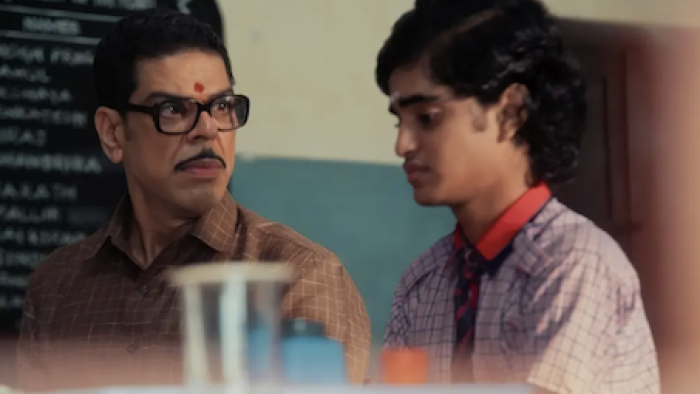 Super Subbu TV show screenshot 2: Cuckoo sitting next to, and sternly looks at, 15-year-old Subbu in a classroom.