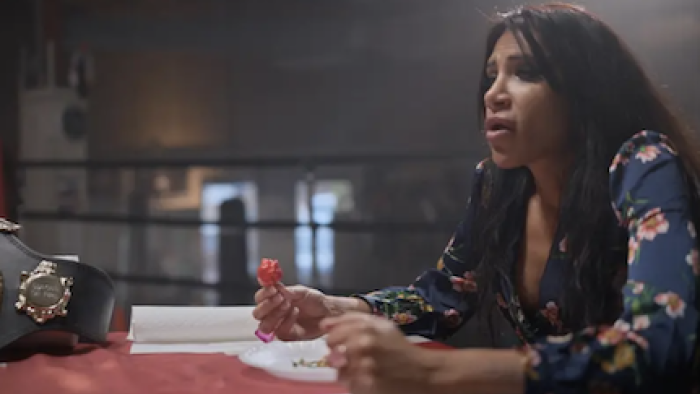 Superhot: The Spicy World of Pepper People screenshot 3: UK champion Shahini Waseem eats a hot pepper next to winner's belt.