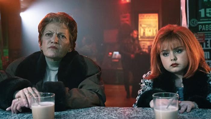 Superstar TV show screenshot 3: A child version of Tamara (in full makeup) sits at a bar with her mother Margarita with two cups of chocolate milk