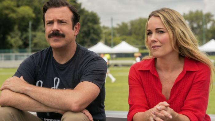 Ted Lasso Season 4: Ted and Michelle sit beside each other on bleachers; Ted has his arms crossed and they look serious