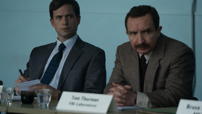 The Bombing of Pan Am 103 TV show screenshot 2: Patrick J. Adams and Eddie Marsan sit at a table with name cards. 