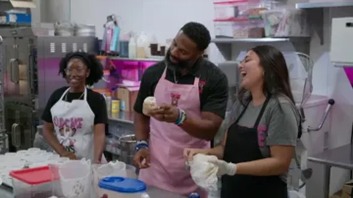 The Cupcake Guys TV Show: Michael Griffin, a black former NFL player, decorates cupcakes with two women employees with brown skin