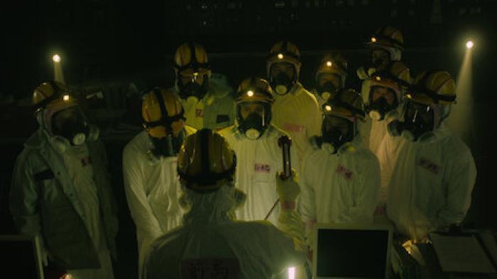 The Days TV show screenshot 1: a meeting between a group of workers in Hazmat suits