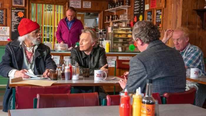 The Full Monty TV show: Horse, Gaz, Dennis, Gerald, and Lomper sit together in The Big Baps cafe; Lomper looks as if he's heard something disturbing, while Horse is bemused by something Gaz is saying. 