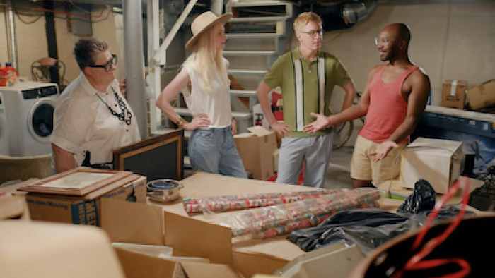 The Gentle Art of Swedish Death Cleaning screenshot 2: Ella, Kat, and Johan stand next to client looking at pile of clutter. 