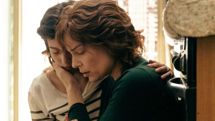 Gaia Girace and Micaela Ramazzotti hugging in front of a bright window.