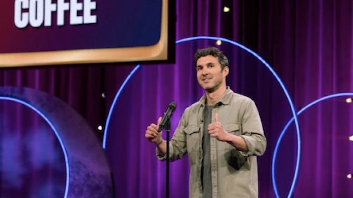 The The Great American Joke Off TV show screenshot 3: A comedian does a stand up bit on mic as part of round. 