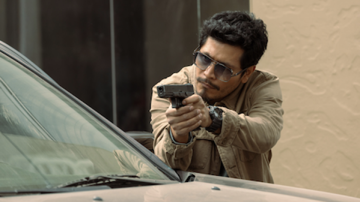 The Gringo Hunters TV show screenshot 3: Officer Nico Bernal posed to shoot behind car. 