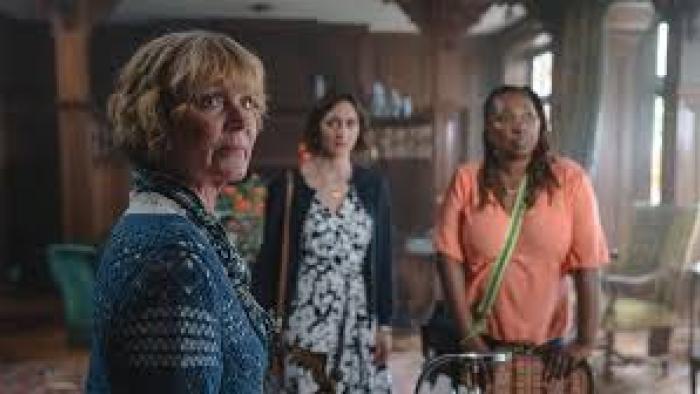 The Marlow Murder Club TV show screenshot #2: three middle-aged women stand together, looking at something in the distance