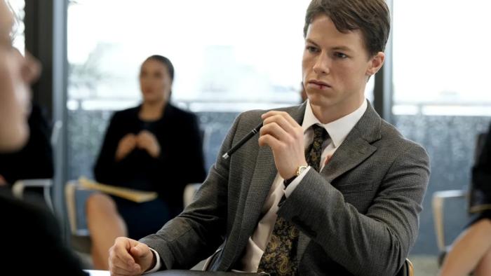 The Rainmaker: Milo Callaghan sits among other lawyers in a boardroom. 