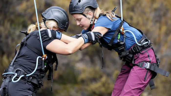 The Summit TV show screenshot 2: Two women in safety gear holding on to eachother.