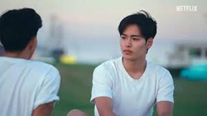 The Boyfriend TV show screenshot: A Japanese man sits on the grass talking to another Japanese man.