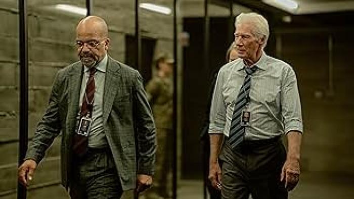 The Agency TV show screenshot: Two middle-aged men, one Black and one White, walk the hallway of an office