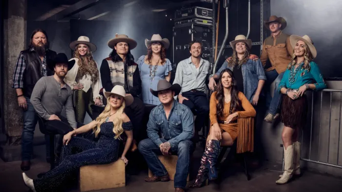 The Road TV show screenshot 1: 12 men and women, roughly 20-50 years old, stand in posed positions with country and western clothing and accessories.
