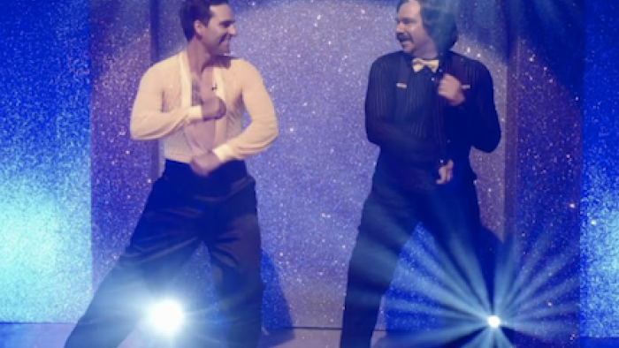 Toast of Tinseltown screenshot 1: Steven Toast dances with male partner on purple stage. 