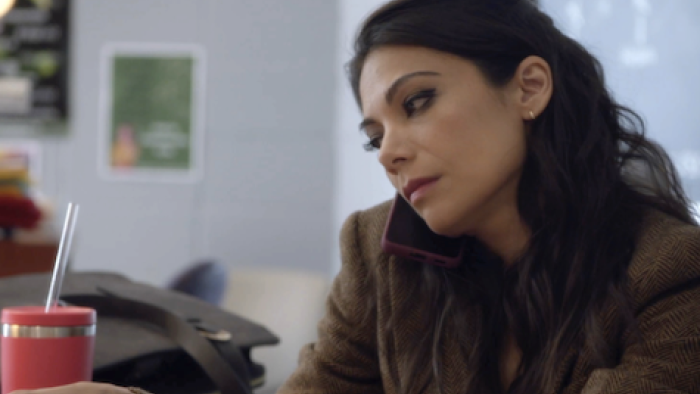 True Lies TV show: Helen holds cell phone to ear with shoulder while sitting in her classroom.