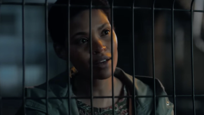 Unseen TV show screenshot 1: Zenzi talks to prison guard through wired gate. 