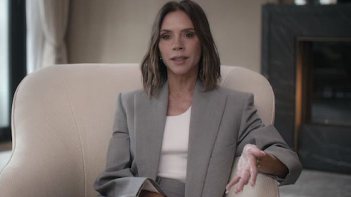 Victoria Beckham TV show screenshot 1: Victoria Beckham sitting in white chair with white shirt and gray jacket