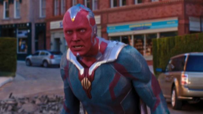 VisionQuest: In his Red Vision skin and Avengers uniform, Vision stares at something dismaying off-screen on a commercial city block