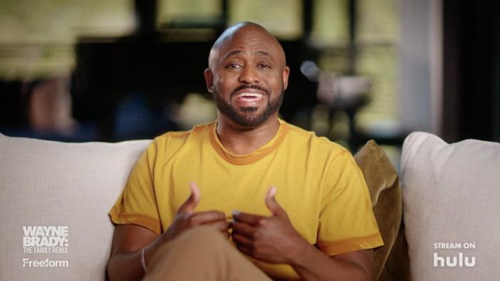 Wayne Brady: The Family Remix TV show screenshot: Wayne Brady sits on his couch smiling and talking to the camera.