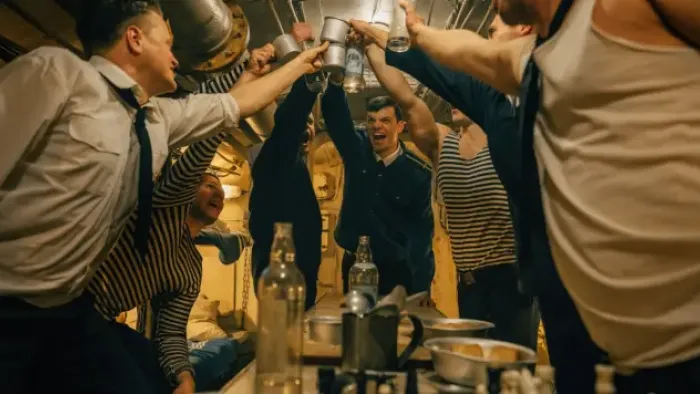 Whiskey on the Rocks TV show screenshot: Men in navy striped shirts, military uniforms and tank tops all hold their arms up in a collective toast.