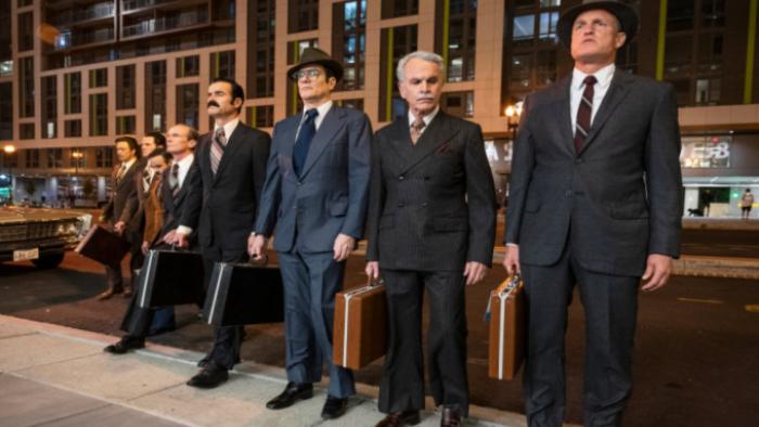 White House Plumbers TV show: Eight men in 1960s-era suits and hats and with briefcases stand in a line on a curb with a city background. Hunt, Liddy, Sturgis, and other Watergate conspirators are visible. 