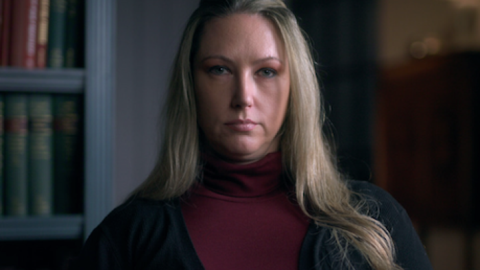 Worst Neighbor Ever screenshot 1: Serious woman with long blonde hair wearing a red turtleneck and black cardigan.