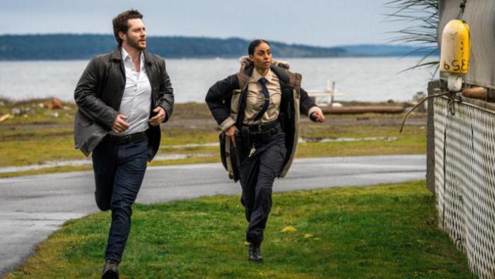 Yaga TV show screenshot 2: Rapp and Carson run towards the camera in an outdoors shot near an ocean view; they appear to be panicked