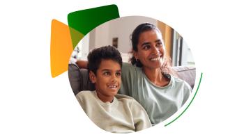 Parent and young child at home watching TV on sofa