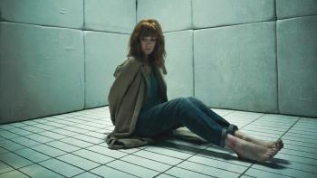 10x10: Kelly Reilly sits in a white padded cell with her legs stretched out in front of her and her hands tied behind her back