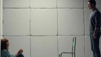 10x10: Kelly Reilly sits against a wall with her hands tied in front of her, while Luke Evans stands behind a chair in front of her