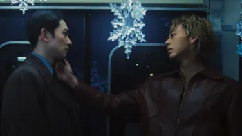 10Dance movie: Japanese man with short black hair, left, faces Japanese man with blond hair, right, who reaches out to touch his face while on a train