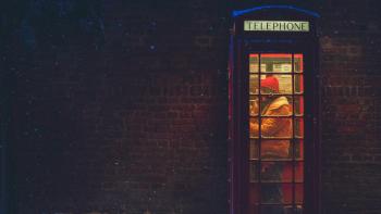 Your Christmas or Mine?: A young biracial woman in a red phone booth.