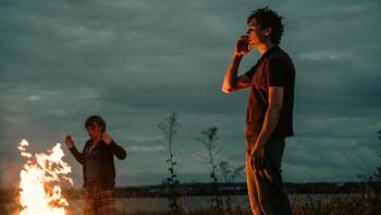 Urchin: A young White man smoking by a fire with a young White woman in the background