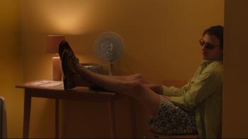 Urchin: A young White man wearing sunglasses with his feet up on a table while sitting inside