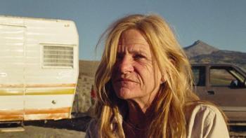 A Love Song: A close-up of a White blond woman in her 60s beside a motorhome