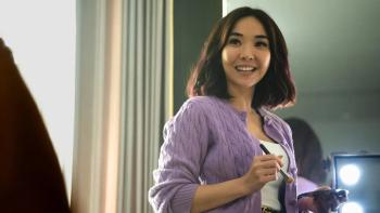A Normal Woman: Erika stands holding a makeup brush and compact smiling broadly at someone off screen.