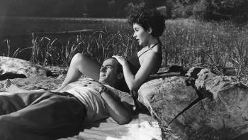 A Place in the Sun: Montgomery Clift lays back to rest his head in Elizabeth Taylor's lap as they relax beside a lake.