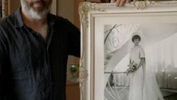 A Tree of Life movie: Anthony Fienberg, wearing a dark shirt and pants,  holds a framed picture of his mother Joyce who was killed at the Tree of Life synagogue