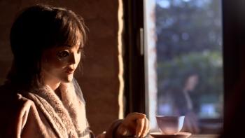 Abruptio Movie: Chelsea (voiced by Hana Mae Lee) sits at a table and reaches for a cup of tea