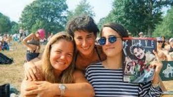 Ahead of the Curve: 3 women with arms around each other outside