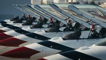 Air Force Elite: Thunderbirds movie: 6 F-16 jets on the ground lined up, 6 pilots in red helmets sitting in the cockpits, doors up and open