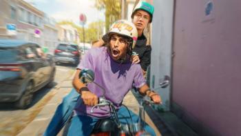 All Time High  scene 1: A man on a small motorcycle with a woman sitting behind him are speeding along a sidewalk narrow sidewalk looking alarmed.