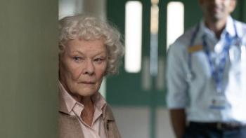 Allelujah: A close-up of Judi Dench peering around a wall with a doctor standing behind her.