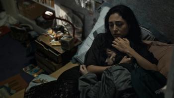 Alpha: A mother comforts her 13-year-old daughter as they both lie in a dimly-lit bedroom